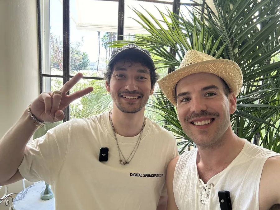 Matthew in a straw hat beside a friend flashing a peace sign.