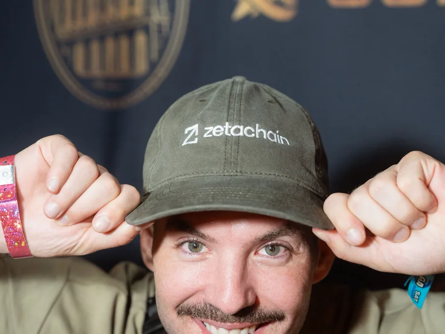 Matthew in a ZetaChain cap and a name tag, grinning.