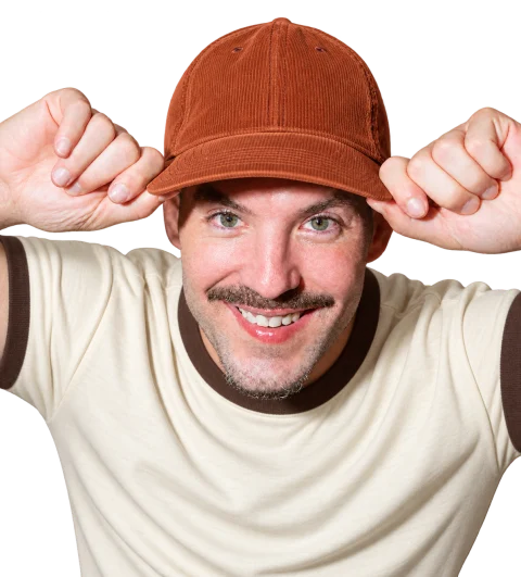 Matthew Karsten in a rust corduroy cap and cream ringer tee, smiling.