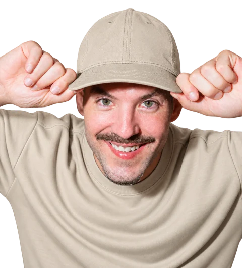 Matthew Karsten in a stone-beige cap and sweatshirt, holding the brim.